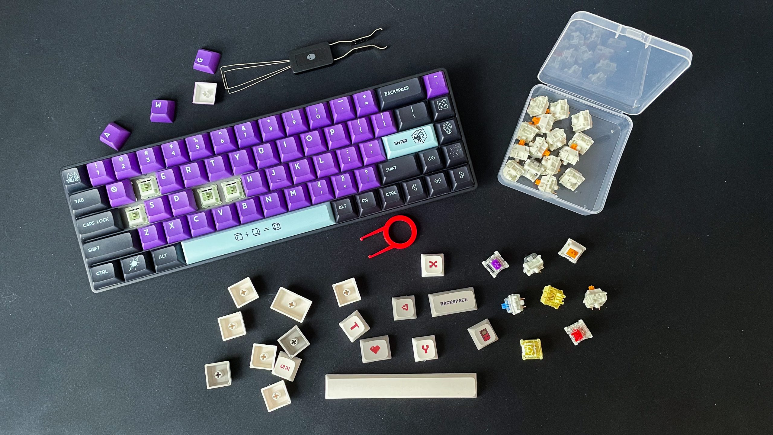 Bàn phím tháo một số keycap, bên cạnh có switch rời và dụng cụ tháo