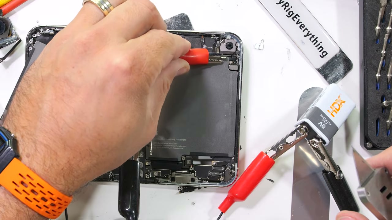 Pin 9V kẹp vào cực pin của iPhone Duo để làm bong keo