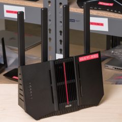 Router Asus RT-BE92U màu đen với bốn ăng-ten đứng đặt trên bàn thử nghiệm.