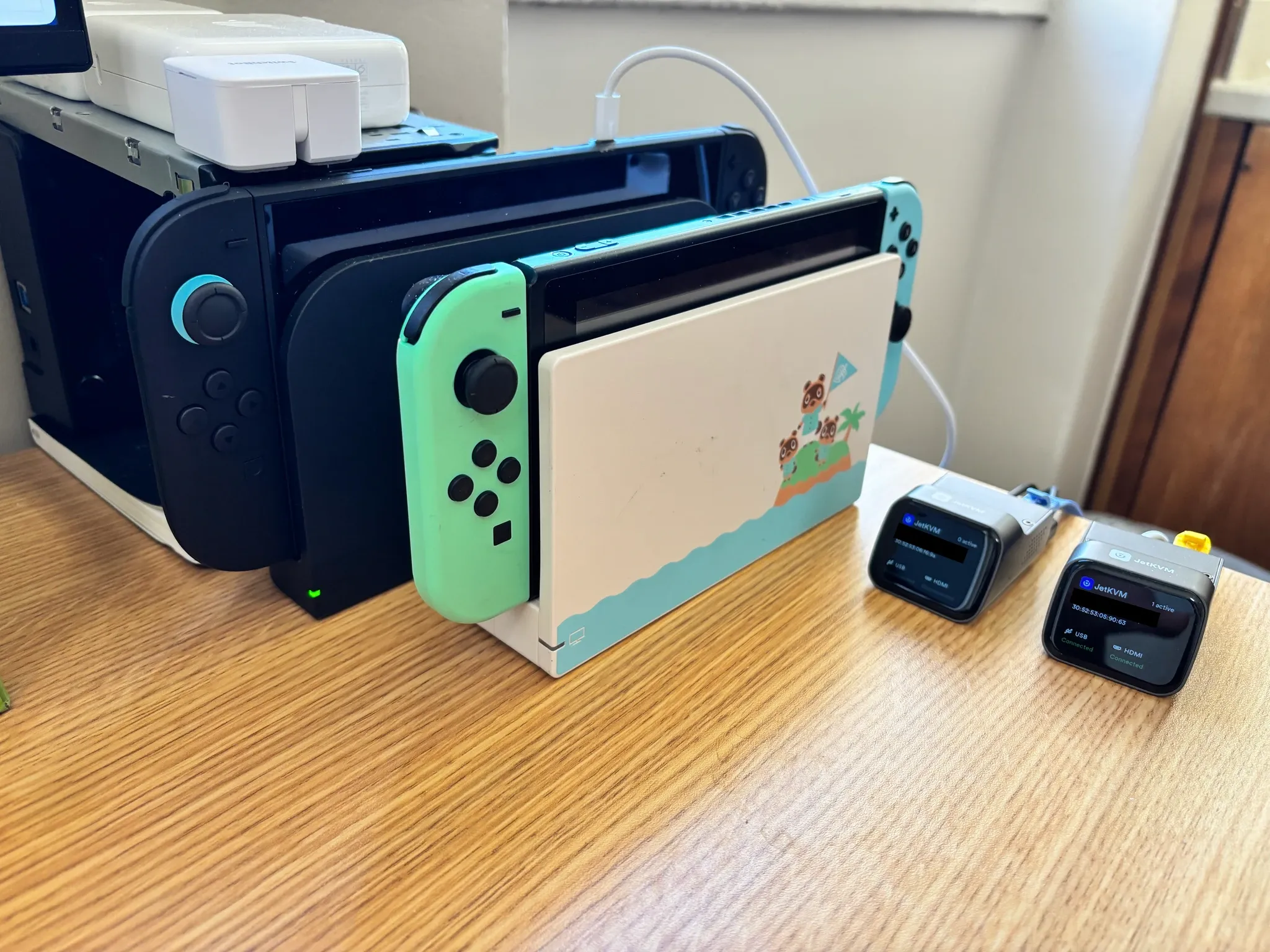 Switch đời đầu và Switch 2 bên cạnh hai thiết bị JetKVM