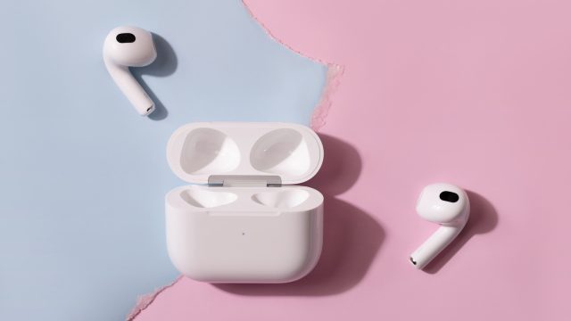 Tai nghe AirPods và hộp sạc mở nắp trên nền hồng xanh