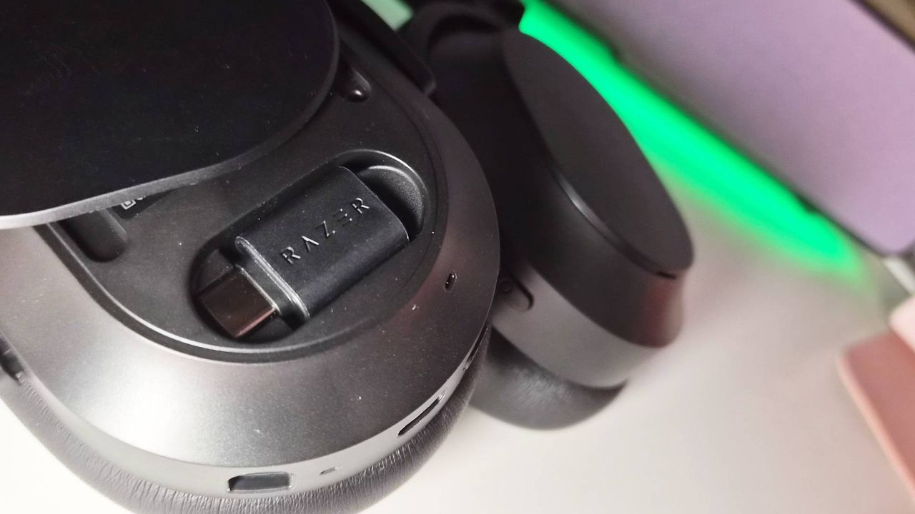 Razer Barracuda V2 Pro với nắp earcup trái mở, để lộ dongle HyperSpeed USB-C trong khoang.