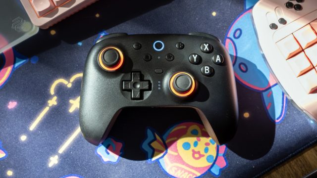 Tay cầm 8BitDo Ultimate 2 đặt trên bàn làm việc cùng dock sạc
