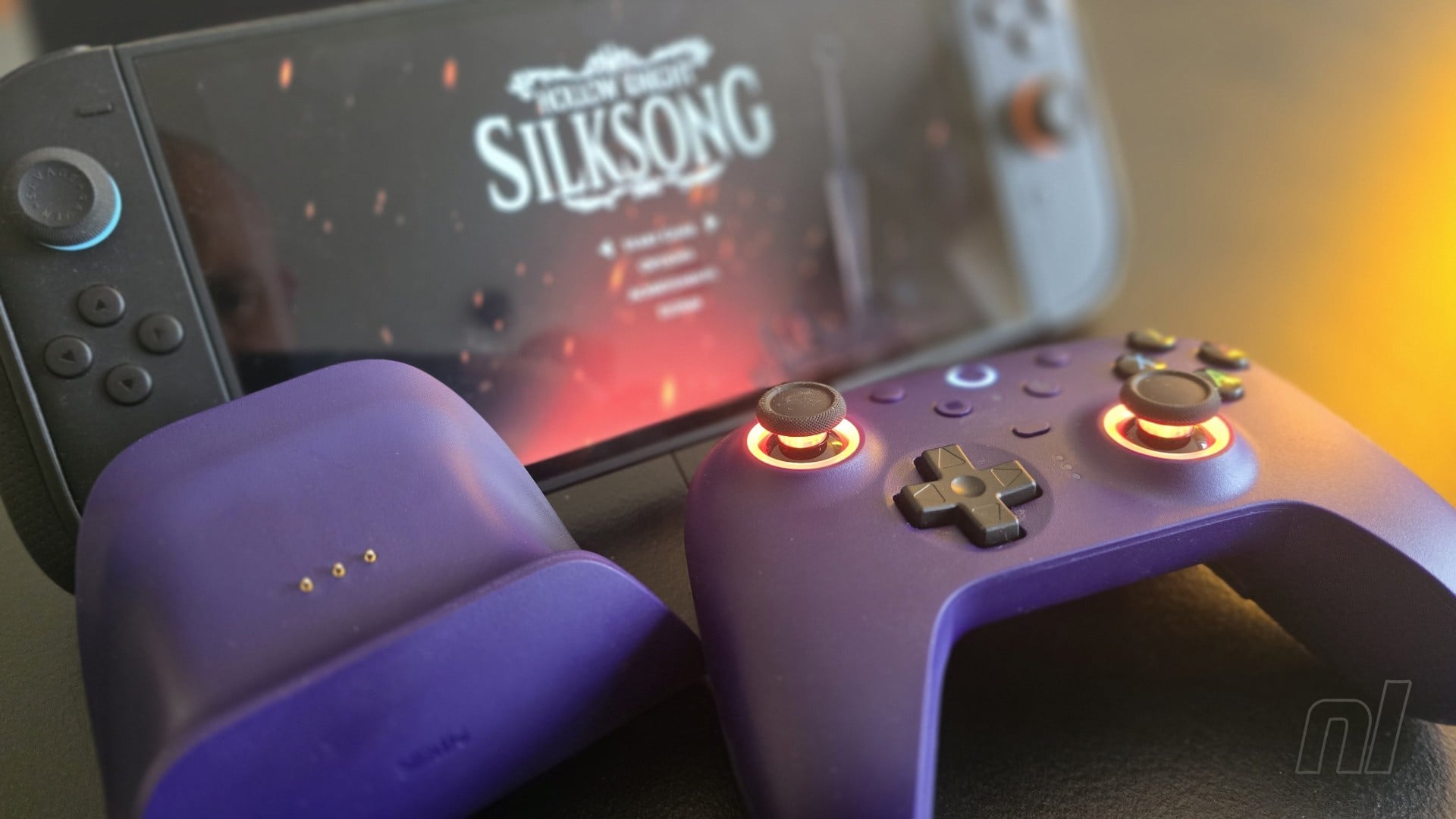 Tay cầm 8BitDo Ultimate 2 màu tím đặt cạnh dock sạc và máy Switch 2