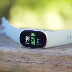 Vòng đeo Fitbit Edge đặt trên mặt bàn gỗ ngoài trời.