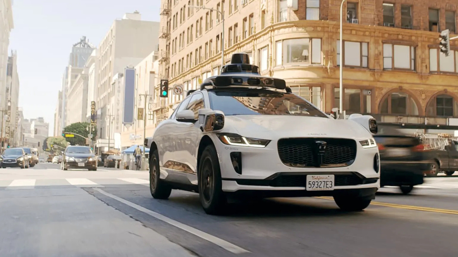 Xe tự hành Waymo màu trắng gắn cảm biến di chuyển trên đường phố